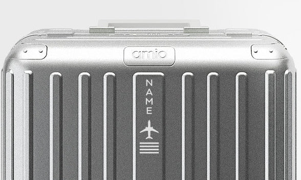 A silver aluminum hard-shell suitcase with vertical ridges and four spinner wheels, shown from a front-facing perspective on a light gray background.